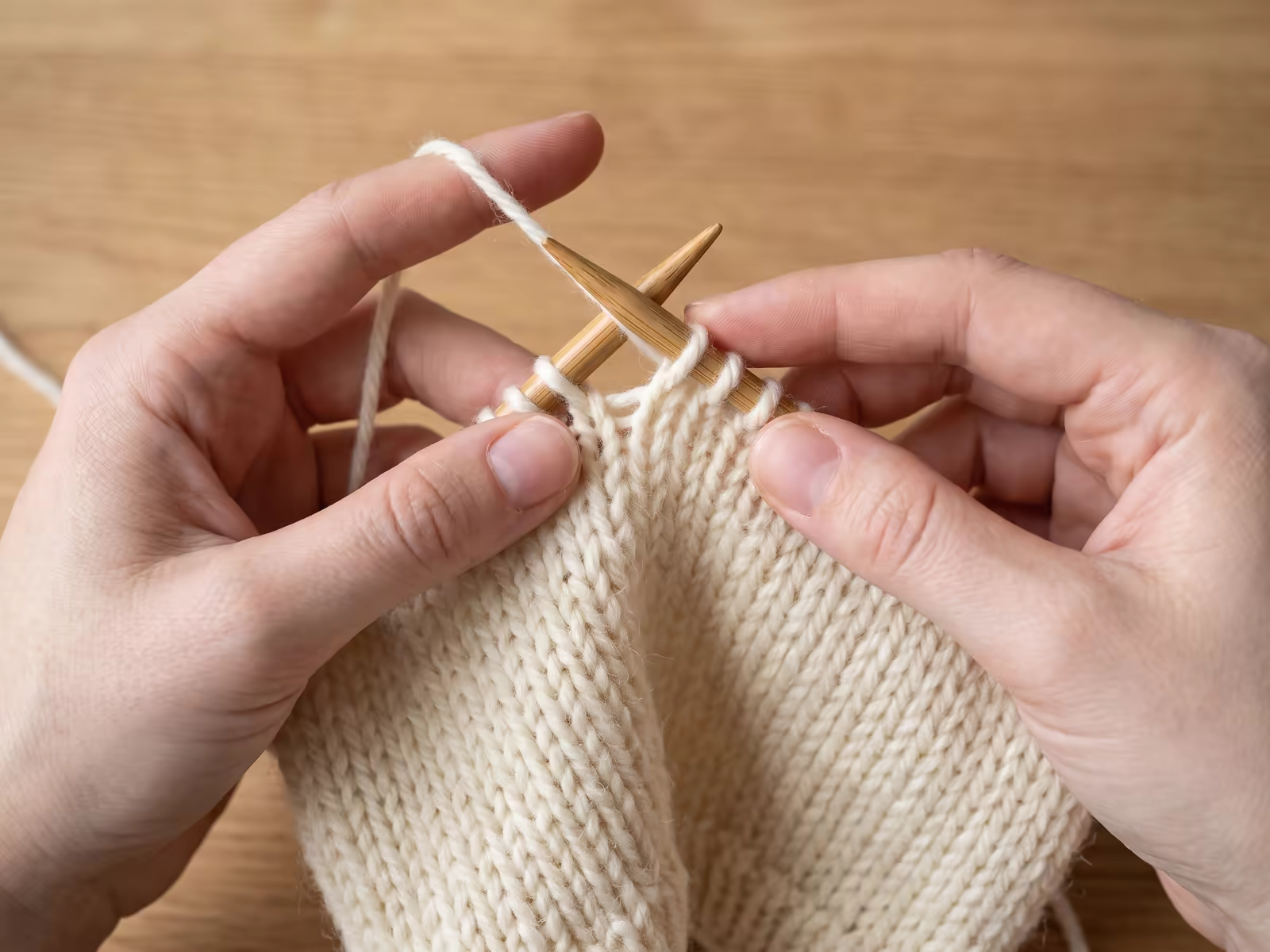Nahaufnahme vom Vorgang, wie eine neue Masche auf der Stricknadel zugenommen wird.