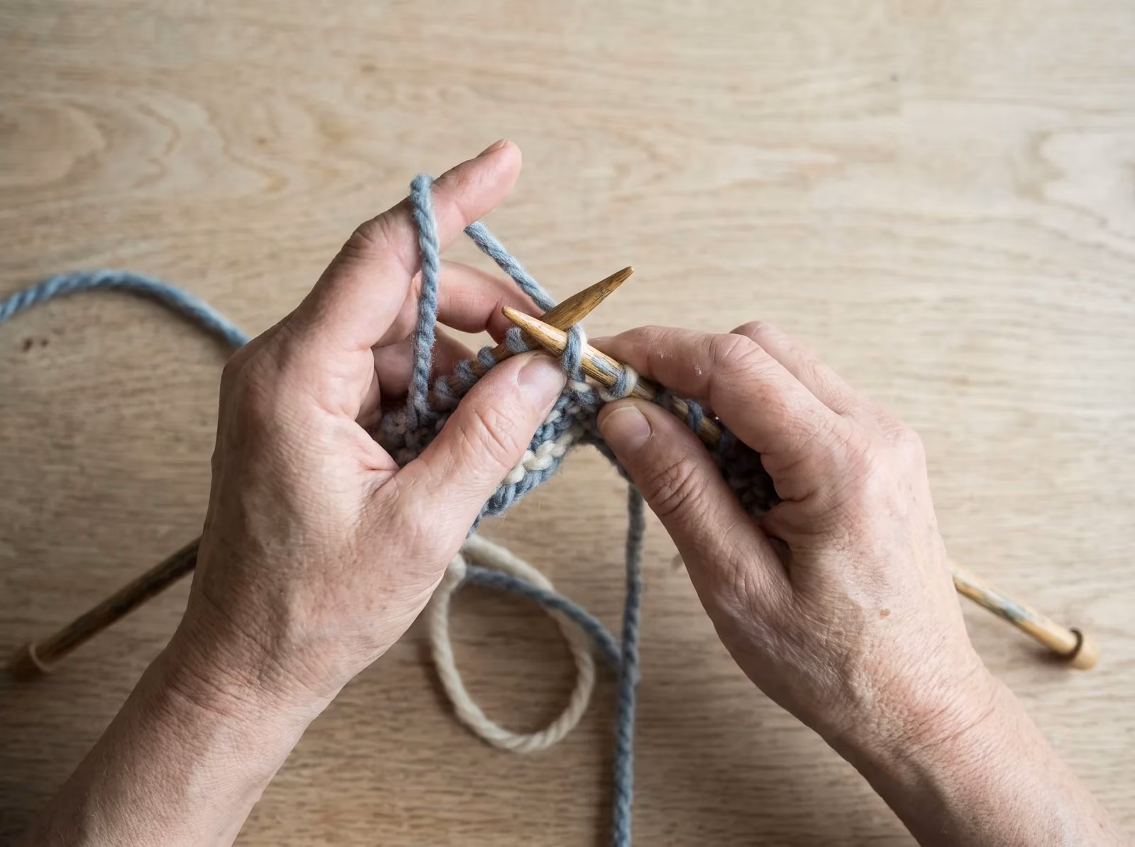 Hände stricken Patentmuster mit einer abgehobenen Masche und Umschlag