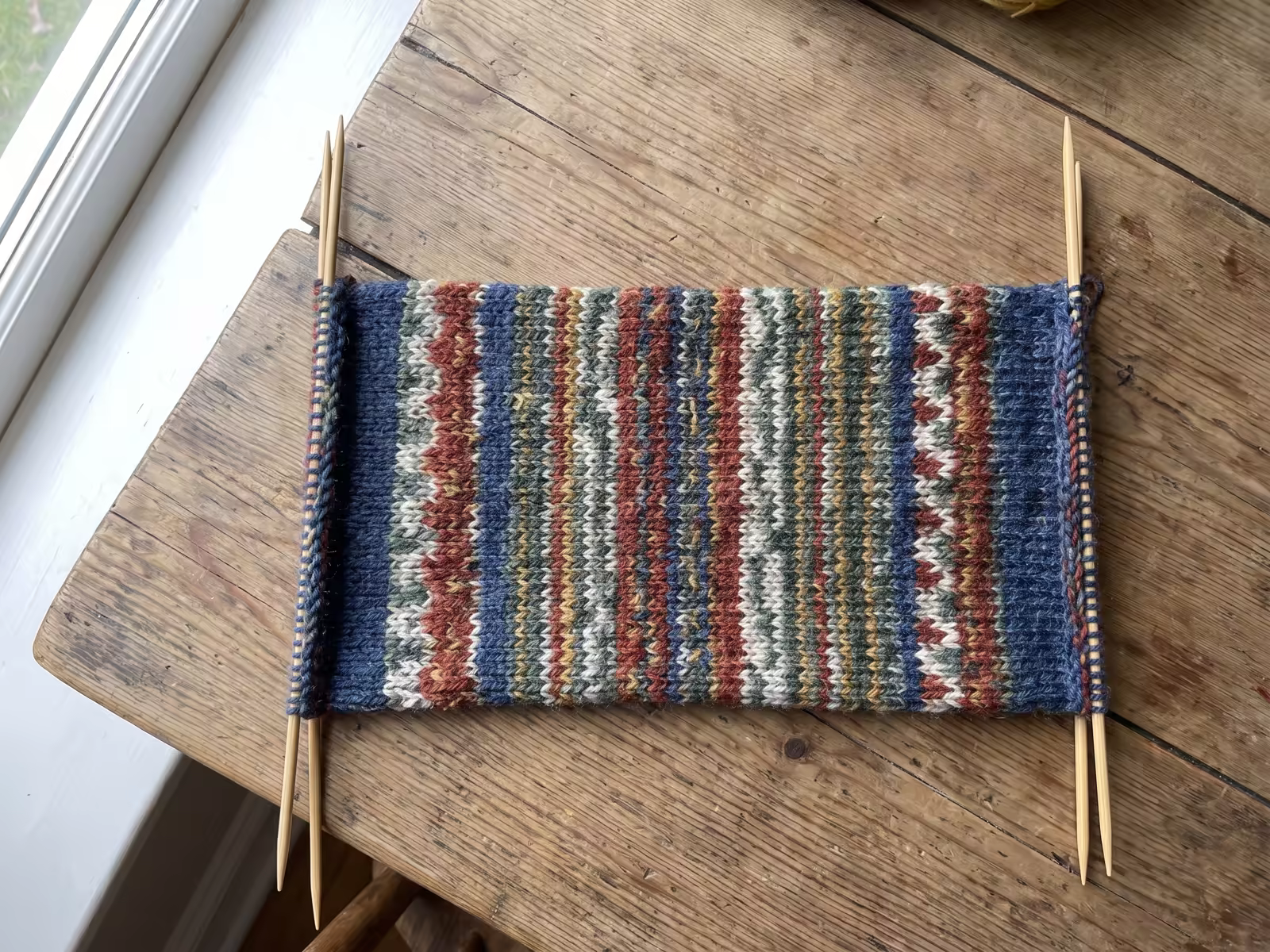 Eine flach auf zwei Nadeln gestrickte Socke liegt bereit zum Zusammennähen.