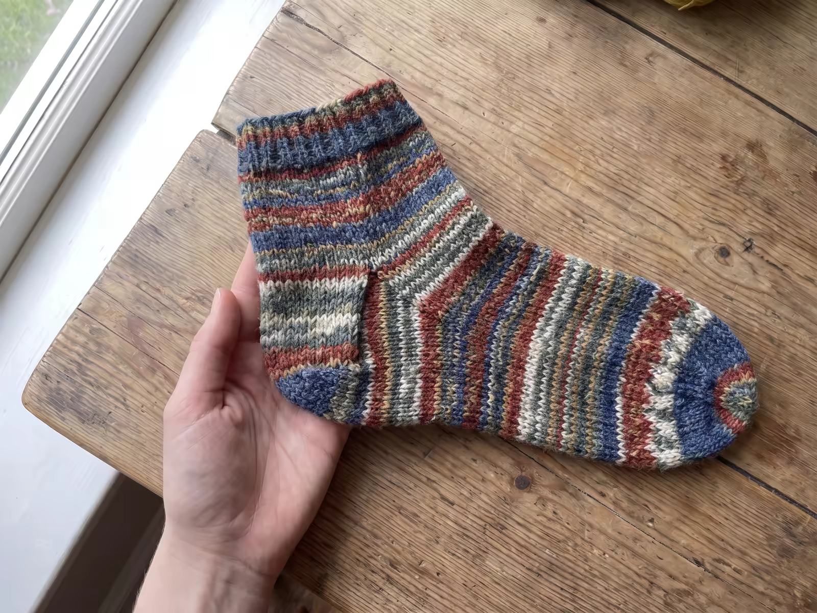 Handgestrickte Socke mit deutlich sichtbarer, sauber gearbeiteter Ferse von der Seite.
